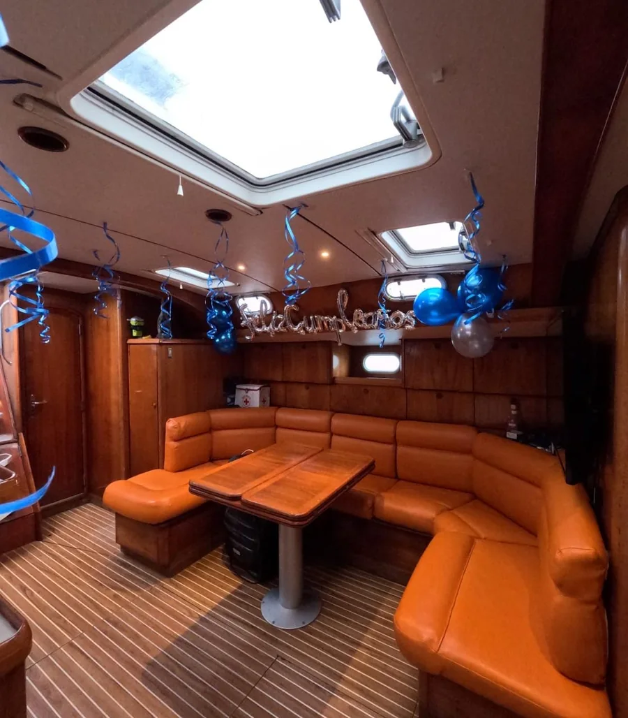 Salón interior del velero, con mesa y sofá en U preparados para un cumpleaños