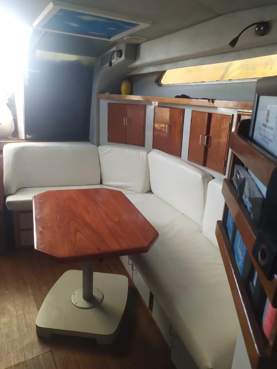 Salón interior del yate, con sofá en U de cuero blanco y mesa de madera